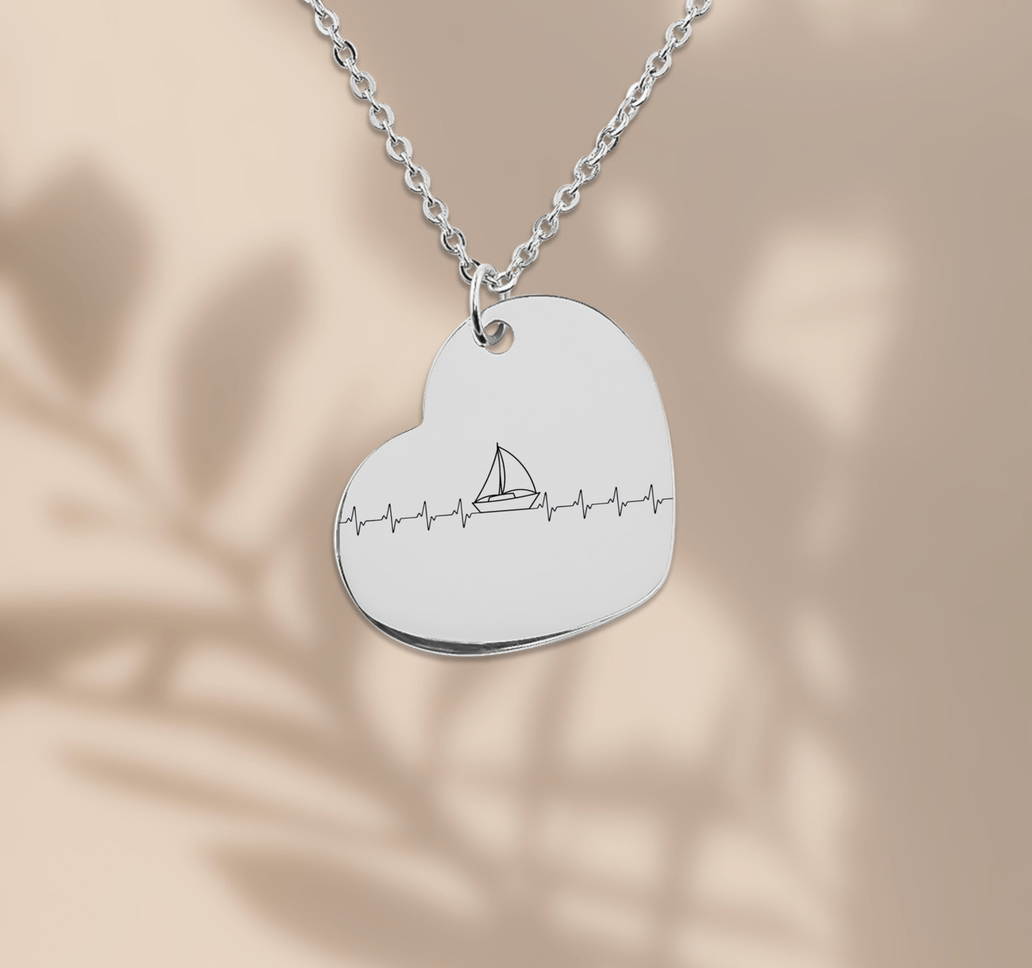 Herz-Halskette mit lasergraviertem Segelboot-Motiv im Herzschlag-Stil, präsentiert in einer schwarzen Geschenkbox mit blauem Hintergrund und poetischen Texten über Wind, Meer und Liebe. Der Anhänger ist herzförmig, 20 x 25 mm groß, aus Edelstahl in Silber, 18 Karat rosègoldplattiert oder 18 Karat vergoldet. Die Kette ist 45 cm lang, mit 5 cm Verlängerung. Ideal als personalisiertes Liebesgeschenk oder zu Weihnachten.