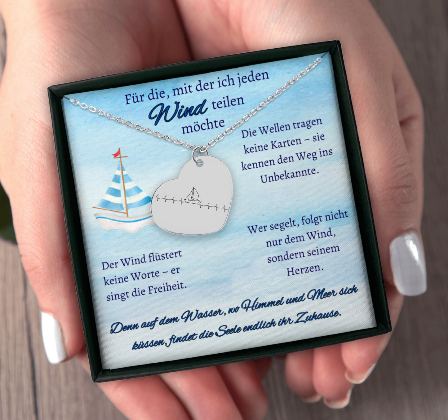 Herz-Halskette mit lasergraviertem Segelboot-Motiv im Herzschlag-Stil, präsentiert in einer schwarzen Geschenkbox mit blauem Hintergrund und poetischen Texten über Wind, Meer und Liebe. Der Anhänger ist herzförmig, 20 x 25 mm groß, aus Edelstahl in Silber, 18 Karat rosègoldplattiert oder 18 Karat vergoldet. Die Kette ist 45 cm lang, mit 5 cm Verlängerung. Ideal als personalisiertes Liebesgeschenk oder zu Weihnachten.