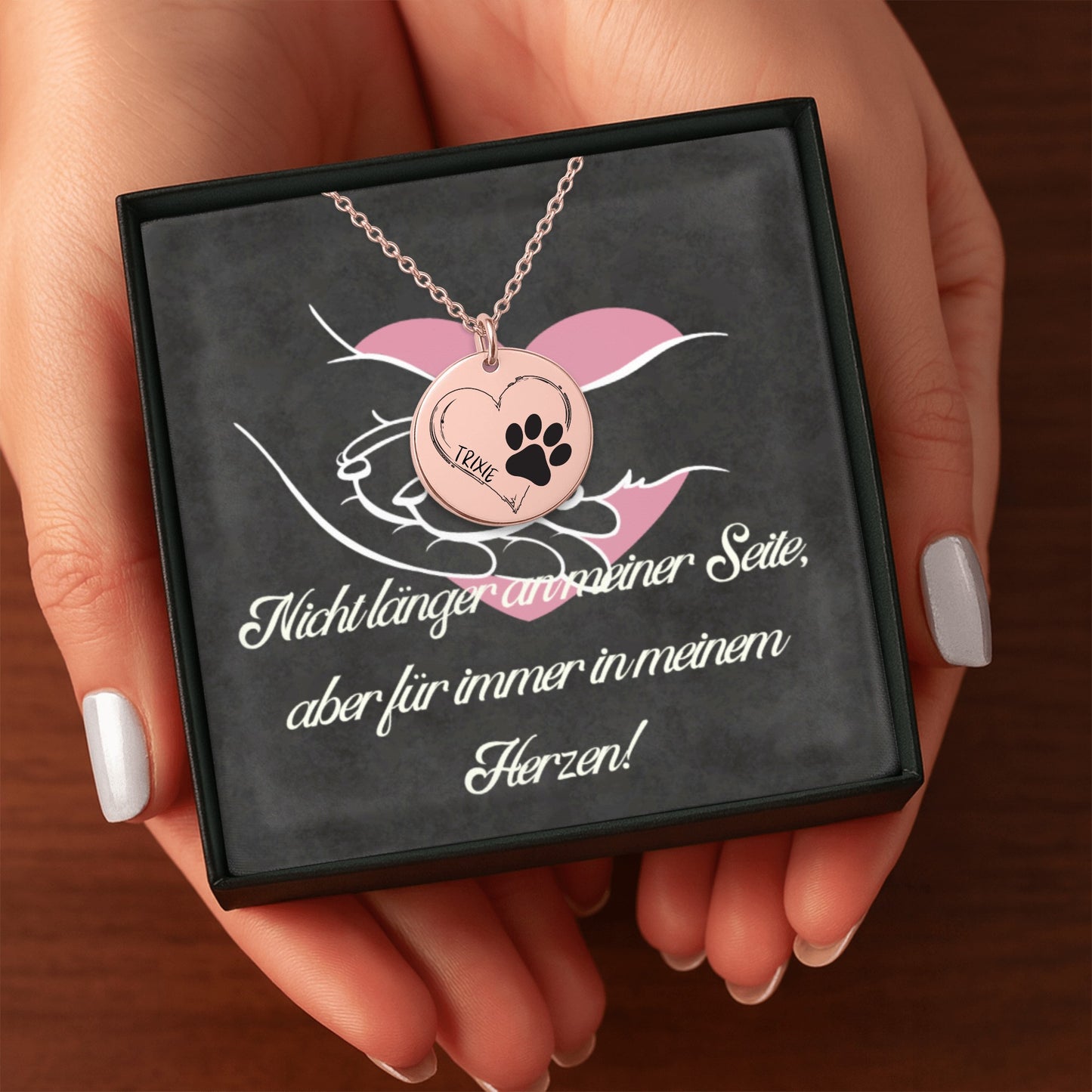 Personalisierte Hundepfoten-Halskette mit rundem Anhänger aus Edelstahl in 18K Goldoptik, Rosé-Gold plattiert oder in Edelstahl Silber. Der Anhänger zeigt eine schwarze Hundepfote, ein Herz und den Namen des Hundes. Die Rückseite kann mit einer persönlichen Lasergravur versehen werden. Die Kette ist 45 cm lang und besitzt eine 5 cm Verlängerung. Ein emotionaler Hund Gedenkschmuck und besonderes Geschenk für Hundebesitzer und Hundeliebhaber zur Erinnerung an einen geliebten Vierbeiner.