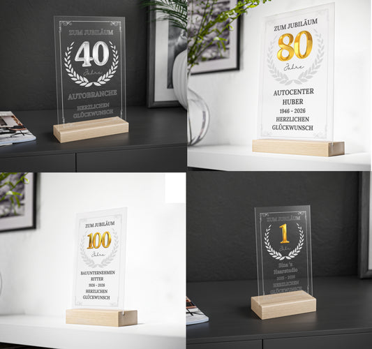 Personalisierte Acryltafel zum Firmen- oder Mitarbeiterjubiläum (10, 25 oder 50 Jahre) auf FSC-zertifiziertem Buchenholzsockel. Mit goldener Zahl, Lorbeerkranz und optionaler LED-Beleuchtung in Größe L. Ideal als Geschenk für langjährige Betriebszugehörigkeit.