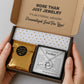 Eine goldene Halskette mit einem runden Anhänger, der mit einem Notenschlüssel und Musiknoten graviert ist. Die Kette wird in einer edlen, schwarzen Geschenkbox auf einer Karte mit einem inspirierenden, emotionalen Spruch präsentiert. Die liebevolle Aufmachung mit zarten Blütenblättern im Hintergrund positioniert den Schmuck als hochwertiges und bedeutungsvolles Geschenk für einen besonderen Menschen.