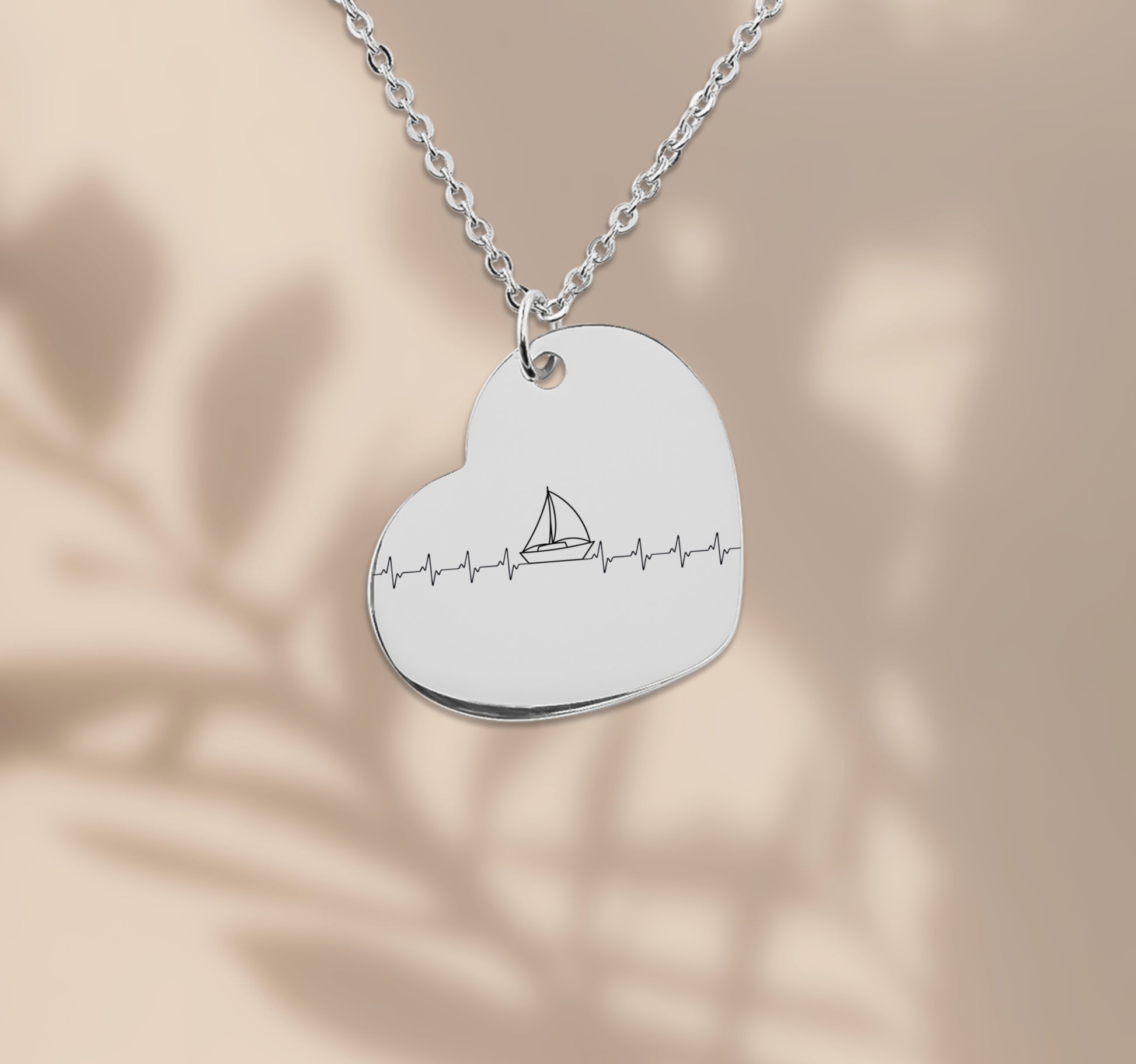 Herz-Halskette mit lasergraviertem Segelboot-Motiv im Herzschlag-Stil, präsentiert in einer schwarzen Geschenkbox mit blauem Hintergrund und poetischen Texten über Wind, Meer und Liebe. Der Anhänger ist herzförmig, 20 x 25 mm groß, aus Edelstahl in Silber, 18 Karat rosègoldplattiert oder 18 Karat vergoldet. Die Kette ist 45 cm lang, mit 5 cm Verlängerung. Ideal als personalisiertes Liebesgeschenk oder zu Weihnachten.