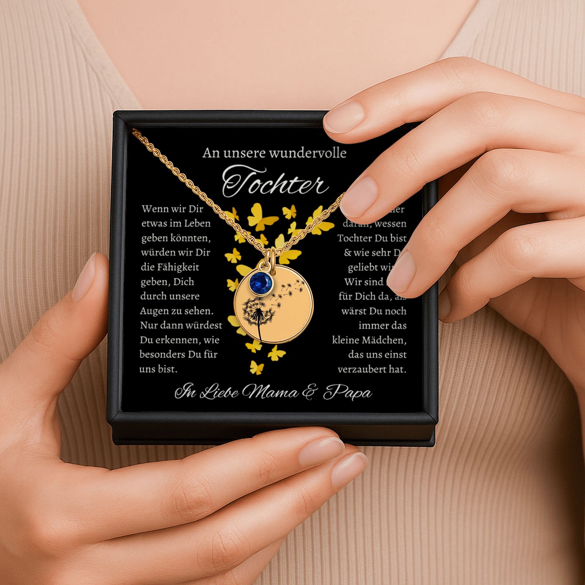 Ein goldenes Collier mit einem runden Anhänger, verziert mit Geburtsstein und einem zarten Pusteblumenmotiv, ruht in einer eleganten schwarzen Geschenkbox. Die Box enthält eine herzliche Botschaft von den Eltern an ihre Tochter, die die tiefe Liebe und den Wunsch ausdrückt, ihr das Beste im Leben zu geben. Die Rückseite des Anhängers ist personalisierbar, ideal für eine Gravur, die diese liebevolle Botschaft oder ein besonderes Datum für immer festhält und das Schmuckstück unvergesslich macht.