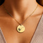 Eine gold Halskette mit runden Anhänger, auf dem eine fein gravierte Windblume abgebildet ist, liegt auf einer weißen Grußkarte in einer schwarzen Schmuckbox. Die Karte trägt die Nachricht: „Liebe Mama – Ohne Dich wäre ich nicht der Mensch, der ich...“ Daneben ist eine zarte Illustration einer Braut. Die 18K vergoldete Edelstahlkette ist 45 cm lang mit 5 cm Verlängerung. Ein emotionales Dankeschön-Geschenk für die Mutter der Braut, liebevoll verpackt und bereit zum Verschenken.