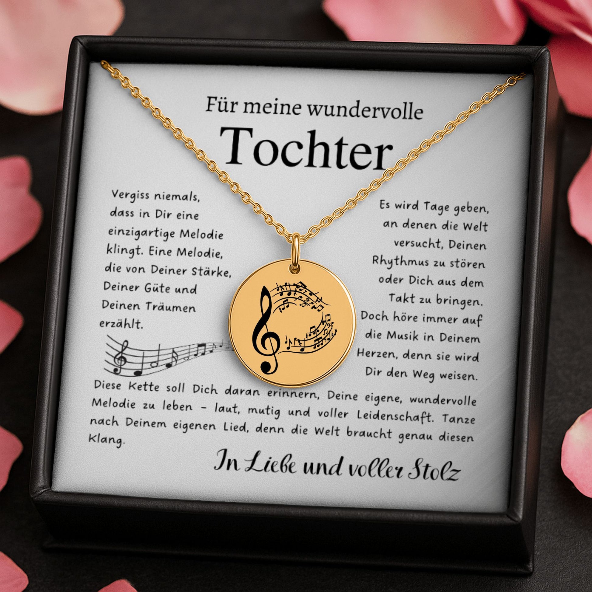 Eine goldene Halskette mit einem runden Anhänger, der mit einem Notenschlüssel und Musiknoten graviert ist. Die Kette wird in einer edlen, schwarzen Geschenkbox auf einer Karte mit einem inspirierenden, emotionalen Spruch präsentiert. Die liebevolle Aufmachung mit zarten Blütenblättern im Hintergrund positioniert den Schmuck als hochwertiges und bedeutungsvolles Geschenk für einen besonderen Menschen.