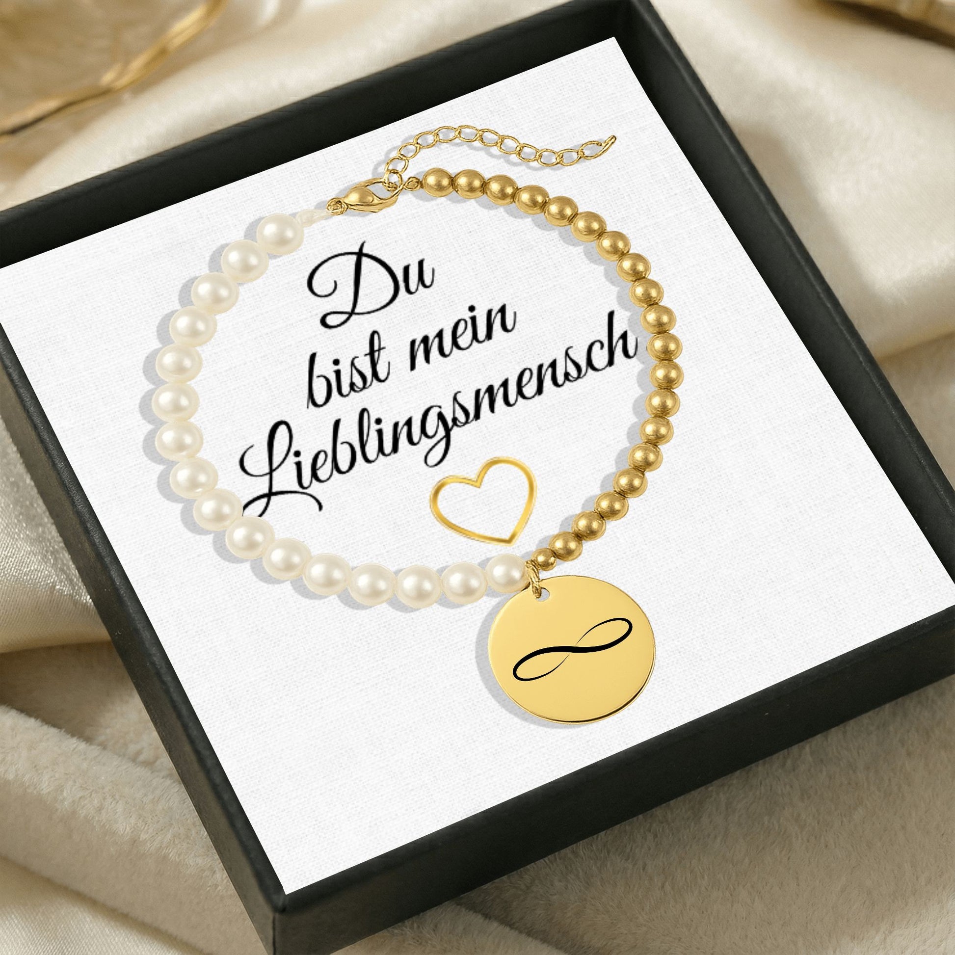 Personalisiertes Perlenarmband mit Namen, bestehend aus weißen Perlmuttperlen und goldfarbenen Edelstahlperlen, mit rundem gravierten Münzanhänger in Gold. Präsentiert in einer eleganten Geschenkbox mit der Aufschrift „Du bist mein Lieblingsmensch“. Emotionales Schmuckgeschenk, ideal als personalisiertes Armband, Namensarmband oder Geschenk zum Valentinstag und Jahrestag.
