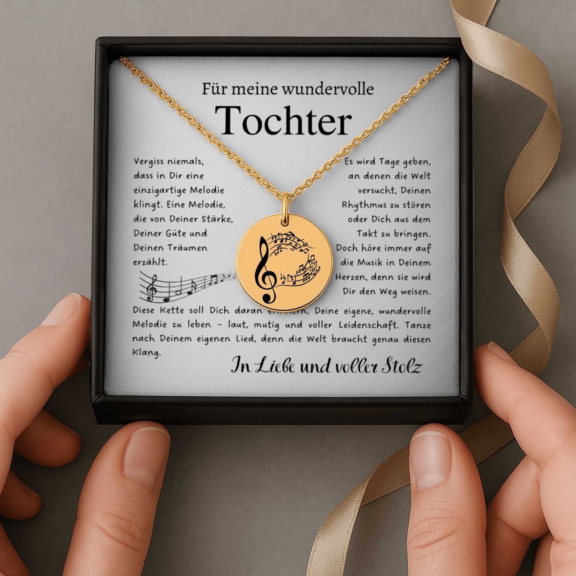 Eine goldene Halskette mit einem runden Anhänger, der mit einem Notenschlüssel und Musiknoten graviert ist. Die Kette wird in einer edlen, schwarzen Geschenkbox auf einer Karte mit einem inspirierenden, emotionalen Spruch präsentiert. Die liebevolle Aufmachung mit zarten Blütenblättern im Hintergrund positioniert den Schmuck als hochwertiges und bedeutungsvolles Geschenk für einen besonderen Menschen.