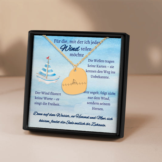 Herz-Halskette mit lasergraviertem Segelboot-Motiv im Herzschlag-Stil, präsentiert in einer schwarzen Geschenkbox mit blauem Hintergrund und poetischen Texten über Wind, Meer und Liebe. Der Anhänger ist herzförmig, 20 x 25 mm groß, aus Edelstahl in Silber, 18 Karat rosègoldplattiert oder 18 Karat vergoldet. Die Kette ist 45 cm lang, mit 5 cm Verlängerung. Ideal als personalisiertes Liebesgeschenk oder zu Weihnachten.