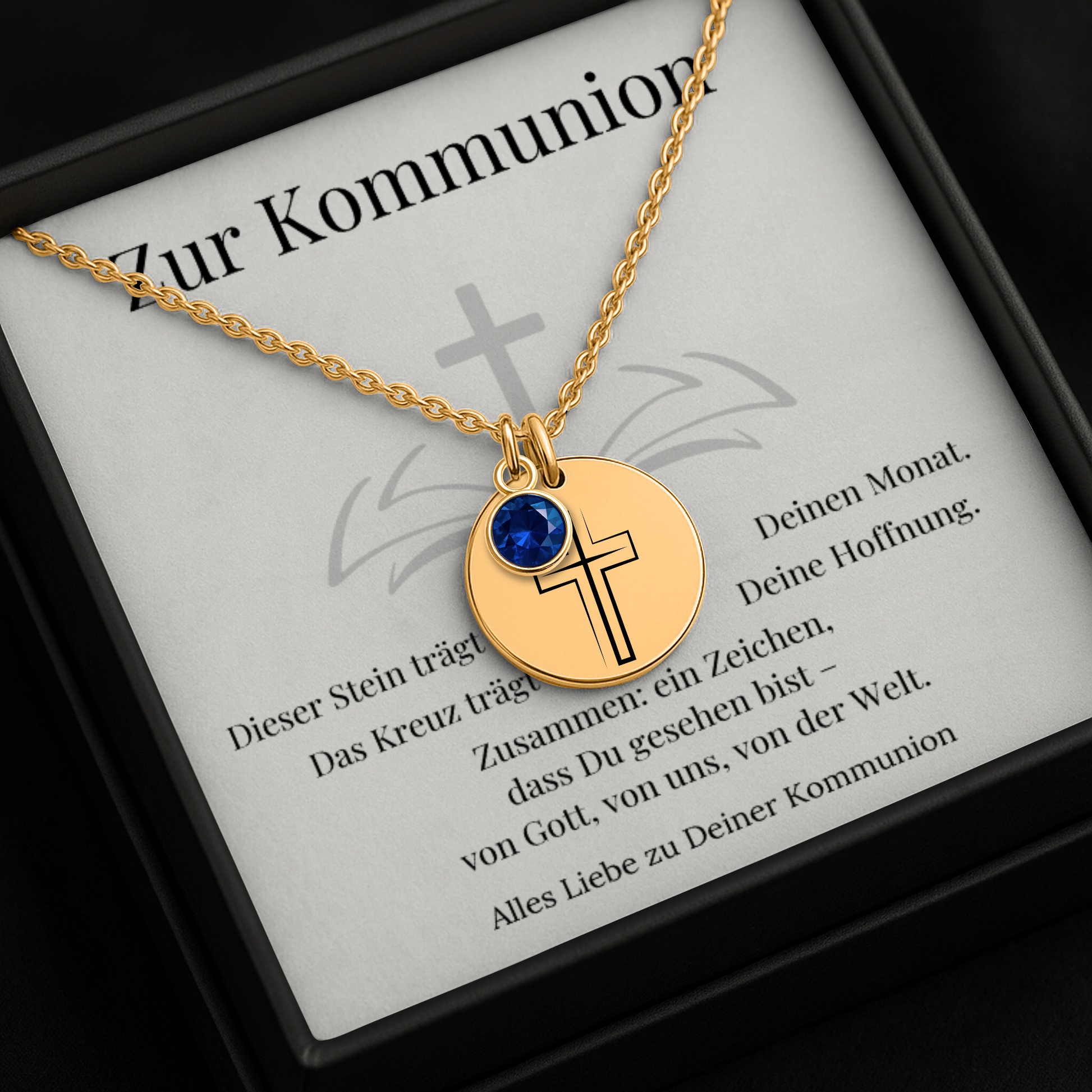 Personalisierte Kommunionskette mit Kreuz-Anhänger und Geburtsstein in 3 Varianten, präsentiert in einer eleganten schwarzen Geschenkbox mit herausnehmbarer Karte. Im Hintergrund rosa Rosenblätter. Ideal als Geschenk zur Erstkommunion für junge Mädchen.