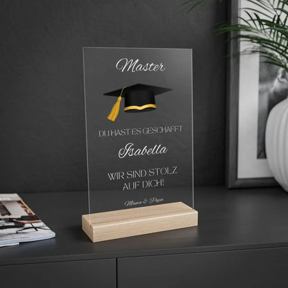 Persönliche Acryltafel mit Name, „Master“-Text, Doktorhut in Schwarz-Gold und individueller Widmung – ein emotionales Geschenk zum Abschluss. Optional Holzsockel mit LED-Lichtern für stimmungsvolle Beleuchtung. Hochwertig gefertigt aus klarem Acryl, ideal als dauerhafte Erinnerung auf Schreibtisch oder Regal. Perfekt als Geschenkidee zum Master, Bachelor oder Doktor – persönlich, edel und langlebig. Ein Geschenk, das Herzen berührt und Erfolge dauerhaft feiert.